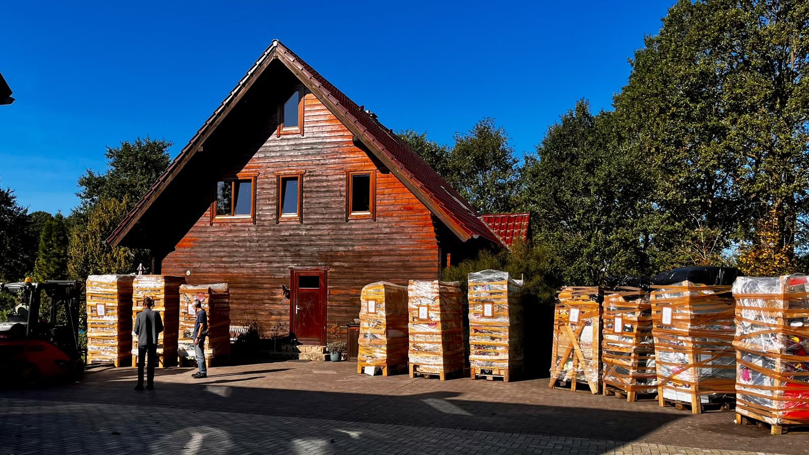 Folierte und nummerierte Paletten stehen vor einem Holzhaus bereit.