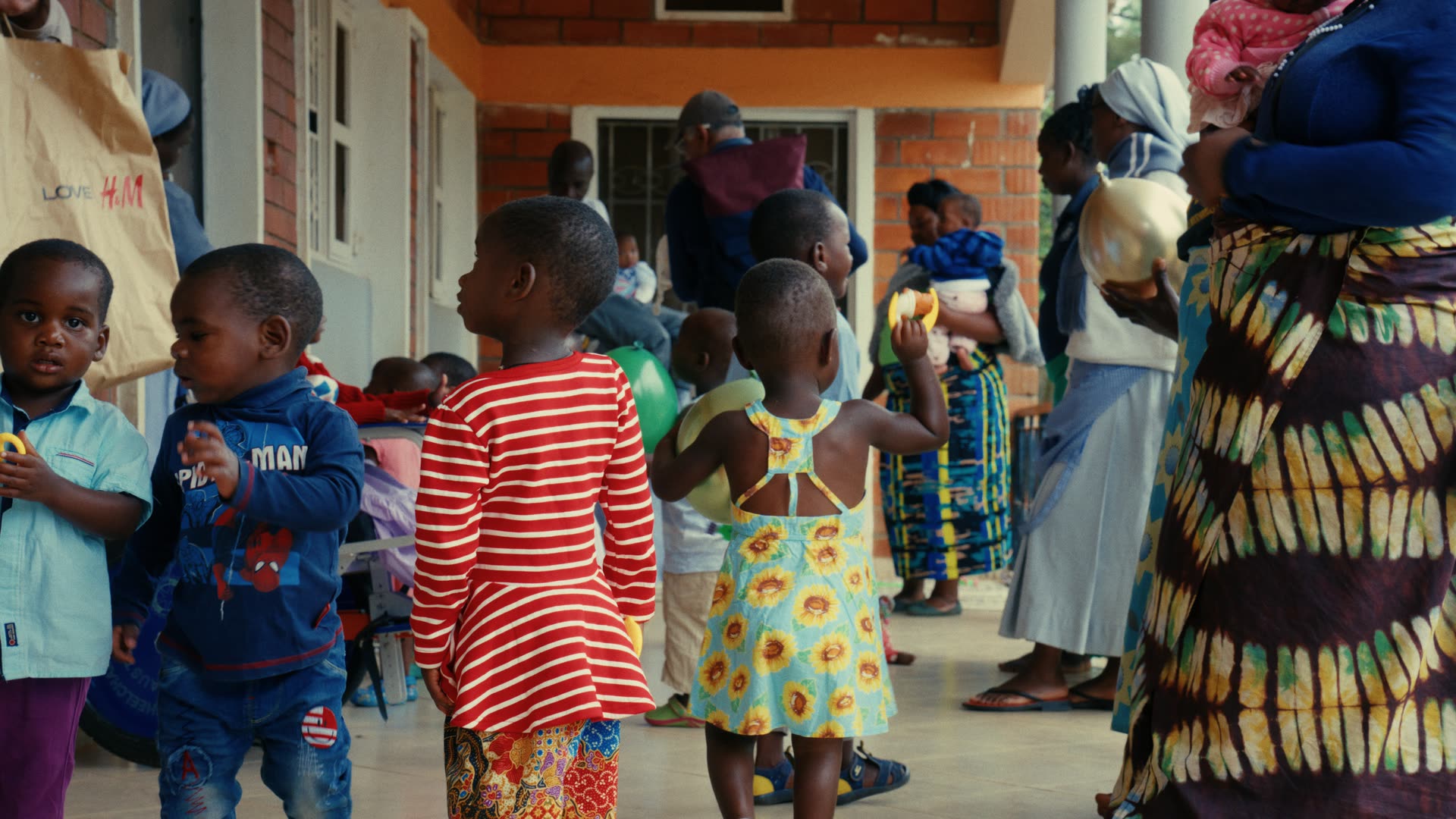 Kinder stehen im Gang einer Gesundheitsstation in Uganda, dahinter warten Frauen mit ihren Kindern.