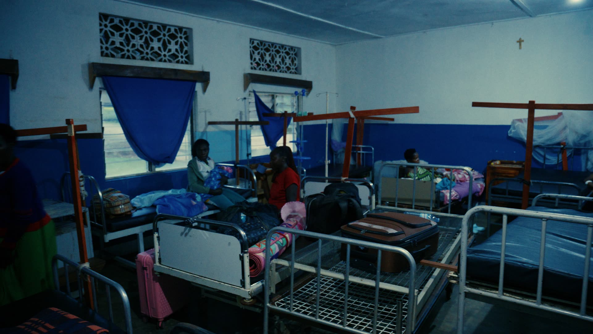 Krankenstation in Uganda: Betten mit Moskitonetzen, dazwischen Patientinnen und Angehörige.