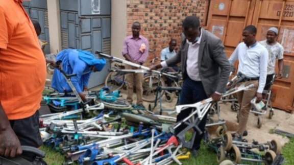 Helfer in Uganda entladen Gehhilfen und Rollstühle aus einem Container der Ugandahilfe Verl.